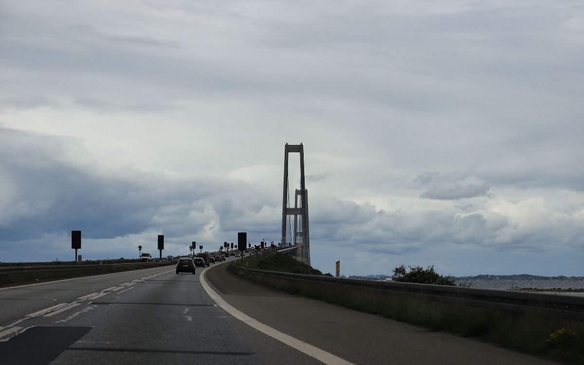 Driving towards the pylons of the Great Belt Bridge under a cloudy sky